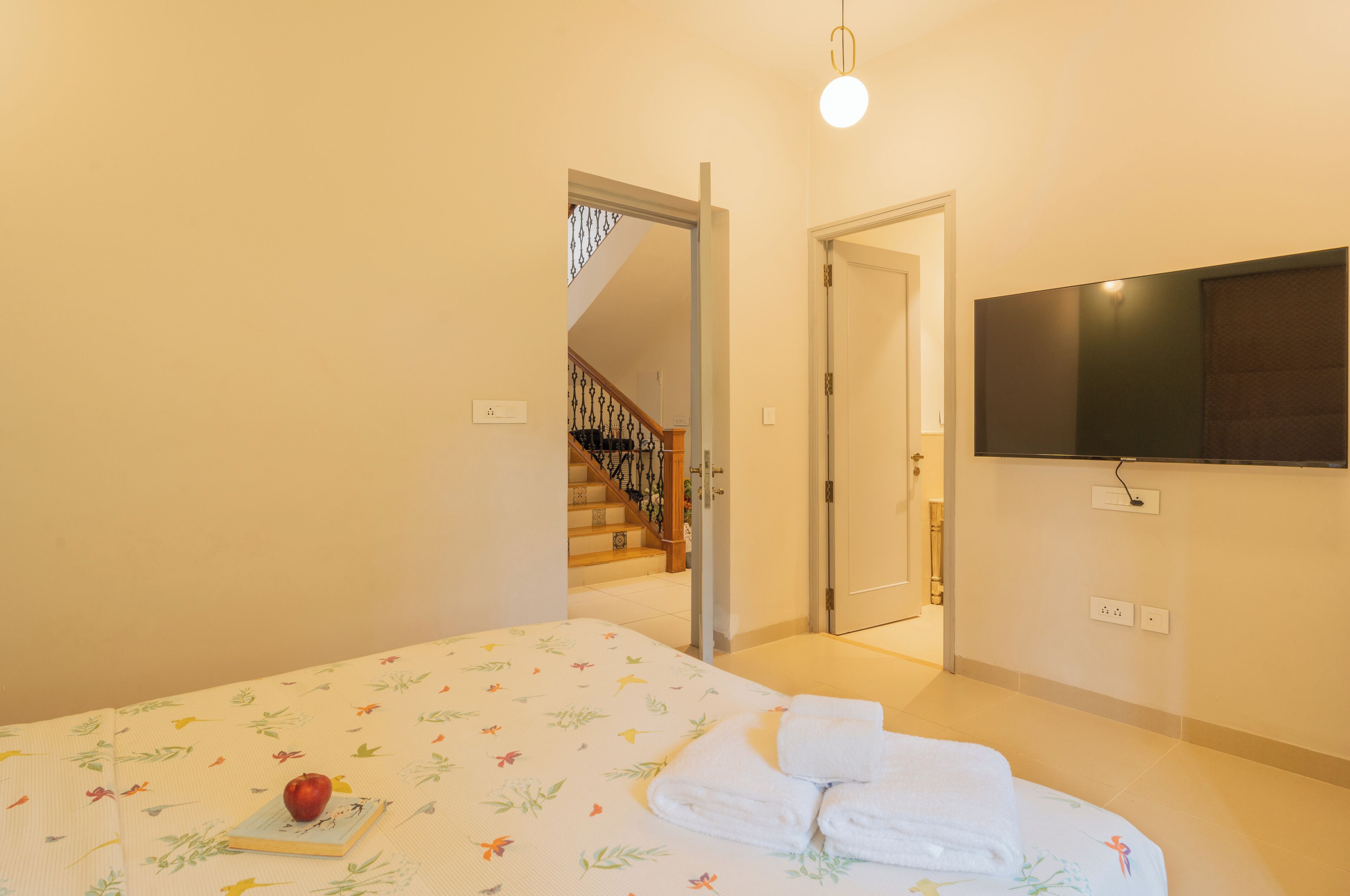 Ein Schlafzimmer mit Bett, einem an der Wand befestigten Fernseher und einer Treppe, die zu einem anderen Raum führt.