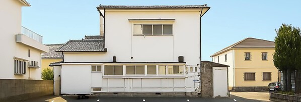 A two-story building with a flat roof, a small balcony, and a garage entrance.