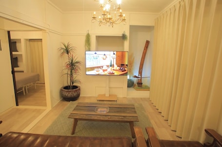 A living room with a television, a chandelier, a potted plant, and a wooden bench.. KG2 MINKAGO Ichikikushikino 73 Private House / Ichikikushikino City Kagoshima
