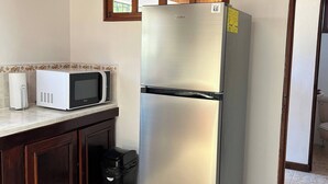 A kitchen with a stainless steel refrigerator, a microwave, and a trash bin. - Charming 3-bedroom House Rental in Paquera, Costa Rica (Paquera)
