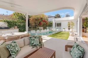 An outdoor living area with a pool, seating, and a view of a modern house. - Burleigh Springs (Pool & Walk to the beach) (Burleigh Heads)