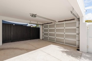 Eine Garage mit einer geschlossenen Metalttür, einem schwarzen Zaun und einem wolkenlosen Himmel.