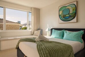 Ein Schlafzimmer mit einem Bett, einer Sitzbank am Fenster und einem Gemälde an der Wand.