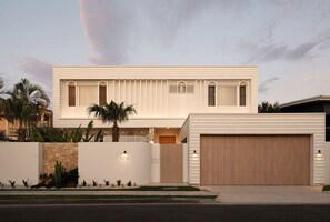 Ein modernes, zweistöckiges Haus mit Garage, Steinmauer und gepflegtem Rasen.