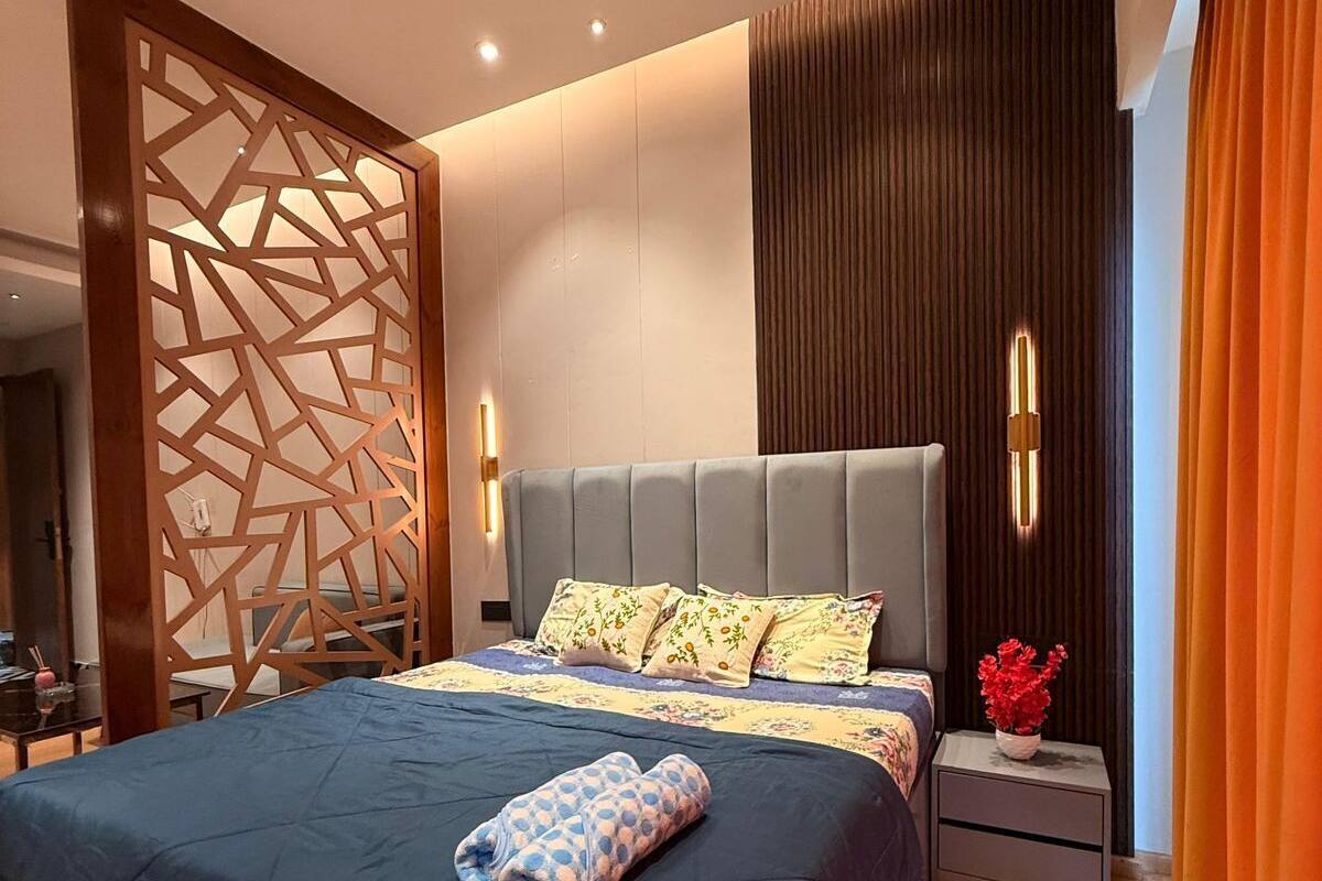A modern bedroom with a large bed, a ceiling fan, and a nightstand with a vase of flowers.