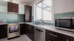 Een moderne keuken met roestvrijstalen apparatuur, een vaatwasser en een raam met uitzicht.