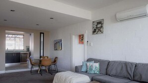 Een moderne woonkamer met een grijze bank, een salontafel en een eethoek met stoelen en een tafel.