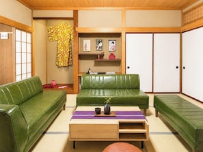 Ein traditioneller japanischer Raum mit einem grünen Sofa, einem Holztisch und einem Teppichboden aus Tatami-Matten.