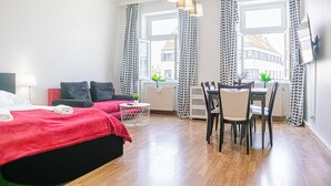 A modern hotel room with a large bed, a dining table with chairs, and a TV mounted on the wall. - Stylish 2BR Apartment Long Stay for 5 (Vienna)