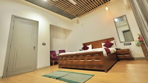 A bedroom with a wooden bed, a ceiling fan, a mirror, and a green mat on the floor. - OnlyStay Kirpalu Dham - Opp. Prem Mandir, Vrindavan (Vrindavan)