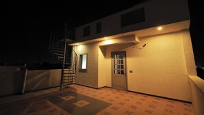 A building exterior at night with a staircase, a door, and a small window. - OnlyStay Kirpalu Dham - Opp. Prem Mandir, Vrindavan (Vrindavan)
