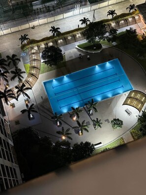 An aerial view of a swimming pool surrounded by palm trees and a curved walkway. - Elegant 1BR Condo Near BGC Prime Taguig Location (Taguig)