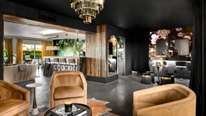 Una hall d'albergo moderna con una zona salotto centrale, un bar e una reception.