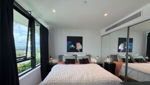 Hotelkamer met een groot bed, nachtkastje, bureau, stoel, raam met gordijnen en een schilderij aan de muur.