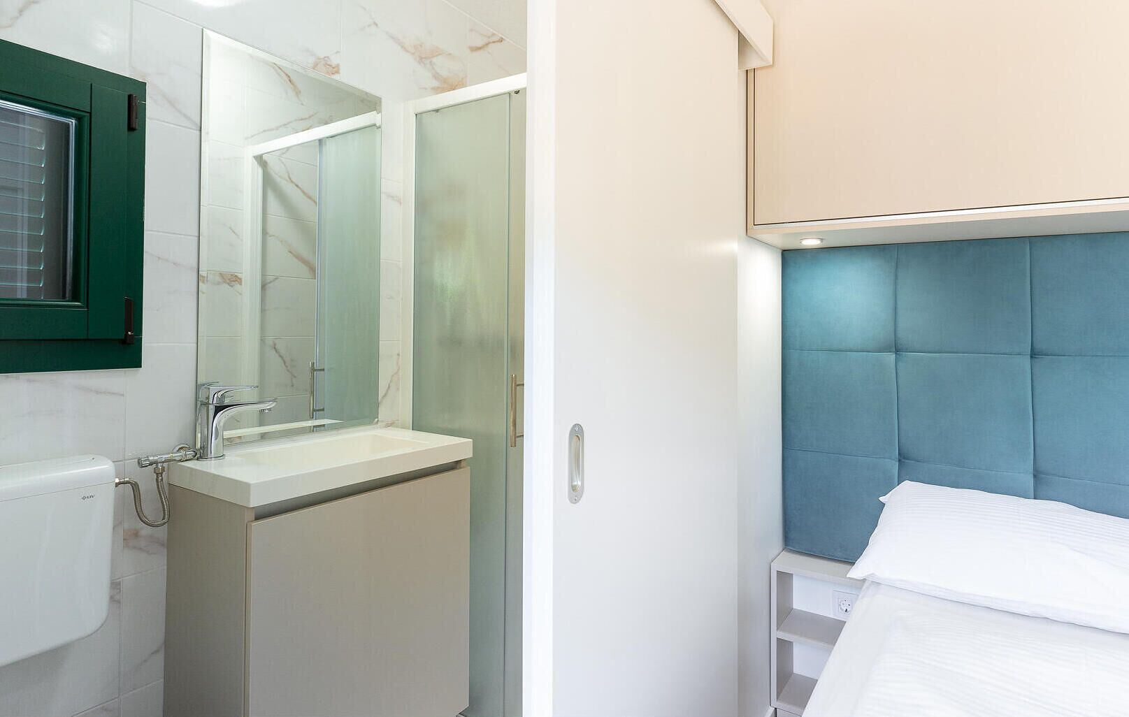 Un baño moderno con ducha de vidrio, lavamanos blanco y espejo.