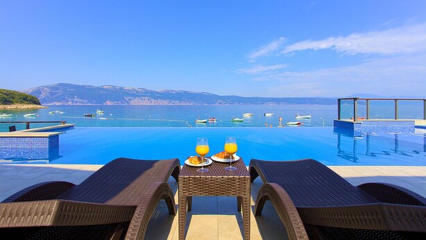 A poolside area with a table set for breakfast, overlooking a sea with boats and hills in the distance. - 2 bedroom lovely (sta)caravan in Glavotok (Glavotok)