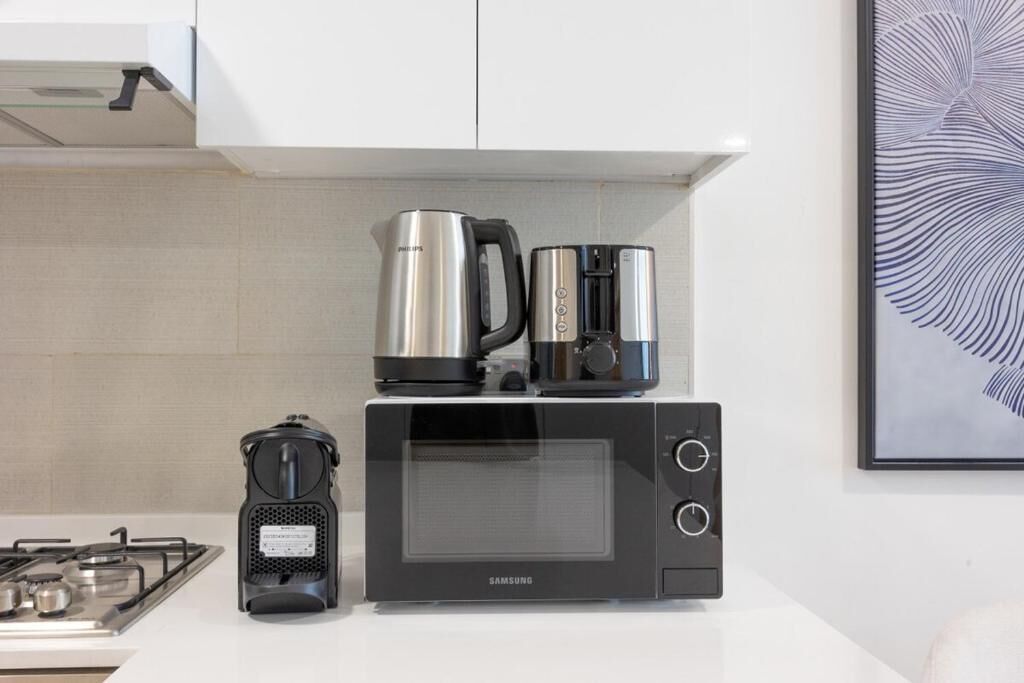 A kitchen with a microwave, a coffee maker, and a gas stove.