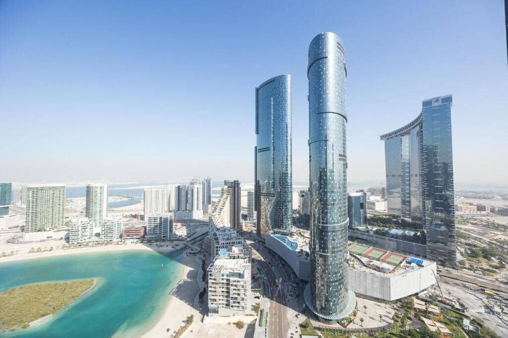 Un paysage urbain moderne avec de hauts immeubles, une plage et un port de plaisance.