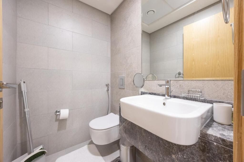 Een moderne badkamer met een witte wastafel, toilet en douche.