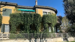 A building with a curved facade, a green awning, and a metal fence in front. - Charming BnB in the Heart of Ravenna in its wonderfull Green! (Ravenna)