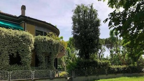 A house with a curved roof, ivy-covered walls, a fenced garden, and a dirt path. - Charming BnB in the Heart of Ravenna in its wonderfull Green! (Ravenna)