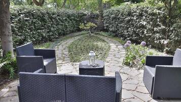 Un patio jardín con mobiliario de mimbre y una mesa con farol.