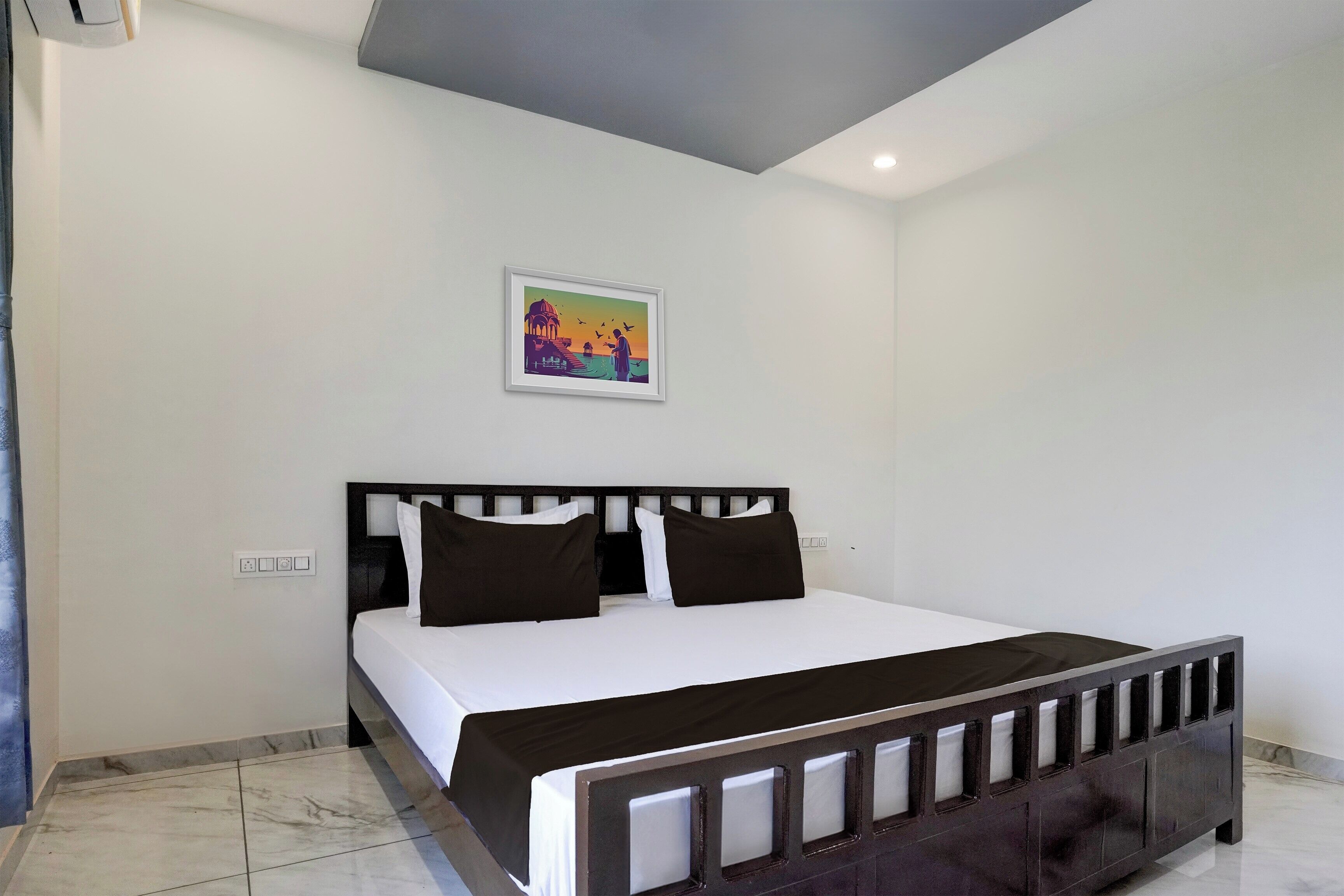 Une chambre à coucher avec un lit, une tête de lit, une table de chevet et un tableau au mur.
