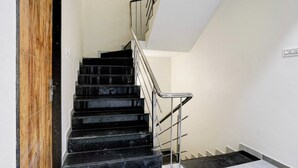 A staircase with black marble steps and a metal handrail, leading to an upper floor. - Hotel Ambika, Vadodara (Waghoriya)