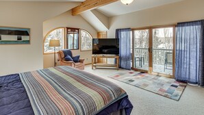A bedroom with a large bed, a TV, a desk, and a view of the outdoors through a sliding glass door. - 4-Season Recreation: Secluded Pike River Cabin (Tower)
