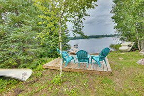 Une terrasse en bois avec des sièges extérieurs et une vue sur un lac.