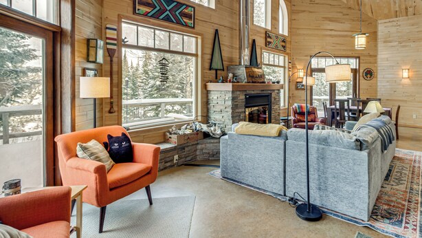 A cozy cabin interior with a stone fireplace, wooden walls, and large windows offering views of trees. - 4-Season Recreation: Secluded Pike River Cabin (Tower)