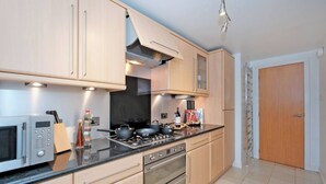 A modern kitchen with light wood cabinets, stainless steel appliances, and a black countertop. - Executive 2Bed City Centre Apartment in Aberdeen (Aberdeen)