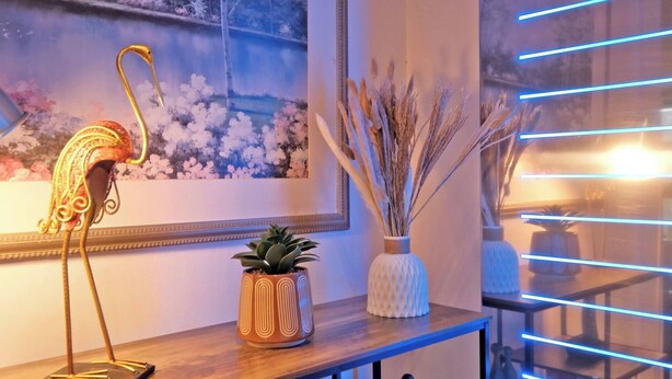 A room with a wooden table, a decorative metal swan, a framed landscape painting, and a vase with dried reeds. - Executive 2Bed City Centre Apartment in Aberdeen (Aberdeen)