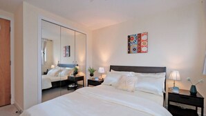 A bedroom with a large bed, bedside tables, a mirror, and a wall art piece. - Executive 2Bed City Centre Apartment in Aberdeen (Aberdeen)