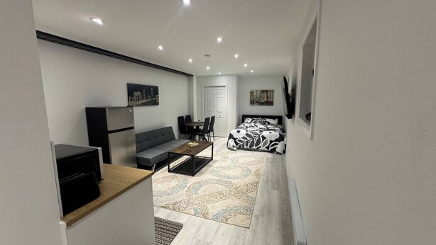 Ein gemütliches Hotelzimmer mit einer Sitzecke, einem kleinen Tisch, einem Bett mit gemustertem Überwurf, einem flachbildfernseher an der Wand und einem Kühlschrank.