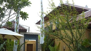 Una casa tradicional con tejado de baldosas, entrada de piedra y abundante vegetación.