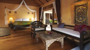 Una habitación tradicional con cama a dosel, un sofá, una mesa de centro de madera y un tapiz decorativo.