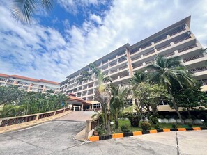 A multi-story hotel with balconies, a covered entrance, and surrounding greenery. - Spacious 2BR Corner Condo - Garden View Balcony - Royal Hill Resort (Pattaya)