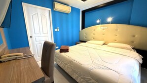 Ein Hotelzimmer mit Bett, Schreibtisch, Stuhl, Tür und Klimaanlage.