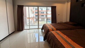 Ein Hotelzimmer mit einem großen Bett, einer Schiebetür zu einem Balkon und Blick auf ein Gebäude mit Balkonen.
