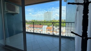 Een balkon met uitzicht op een stadsbeeld, inclusief een hoog gebouw en woongebouwen.
