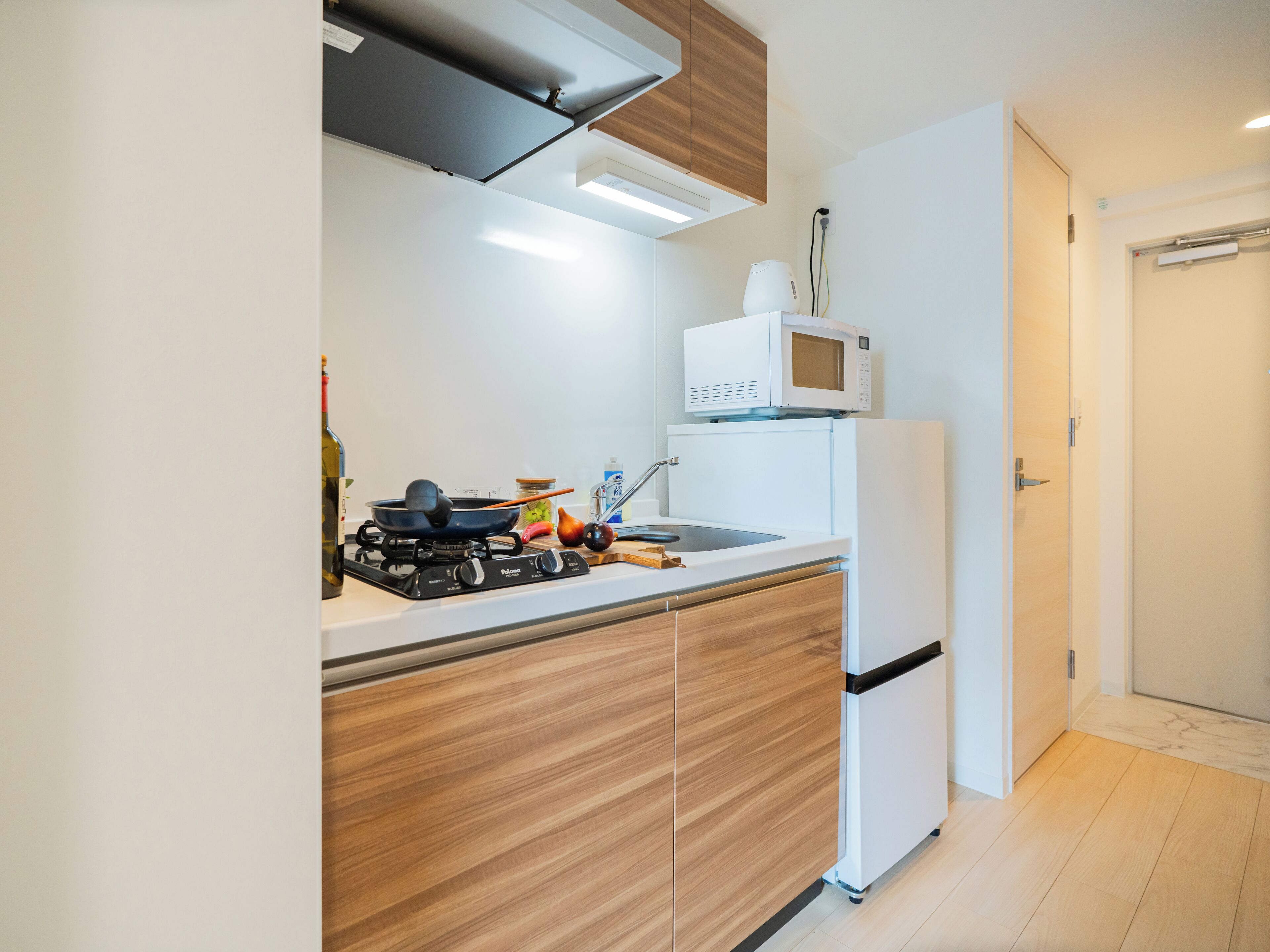 Een kleine keuken met een gasfornuis, een magnetron en houten keukenkastjes.