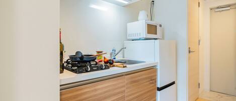 A compact kitchen with a gas stove, a microwave, and wooden cabinets.