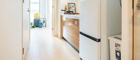 A modern kitchen with a built-in microwave, a refrigerator, and wooden cabinets.
