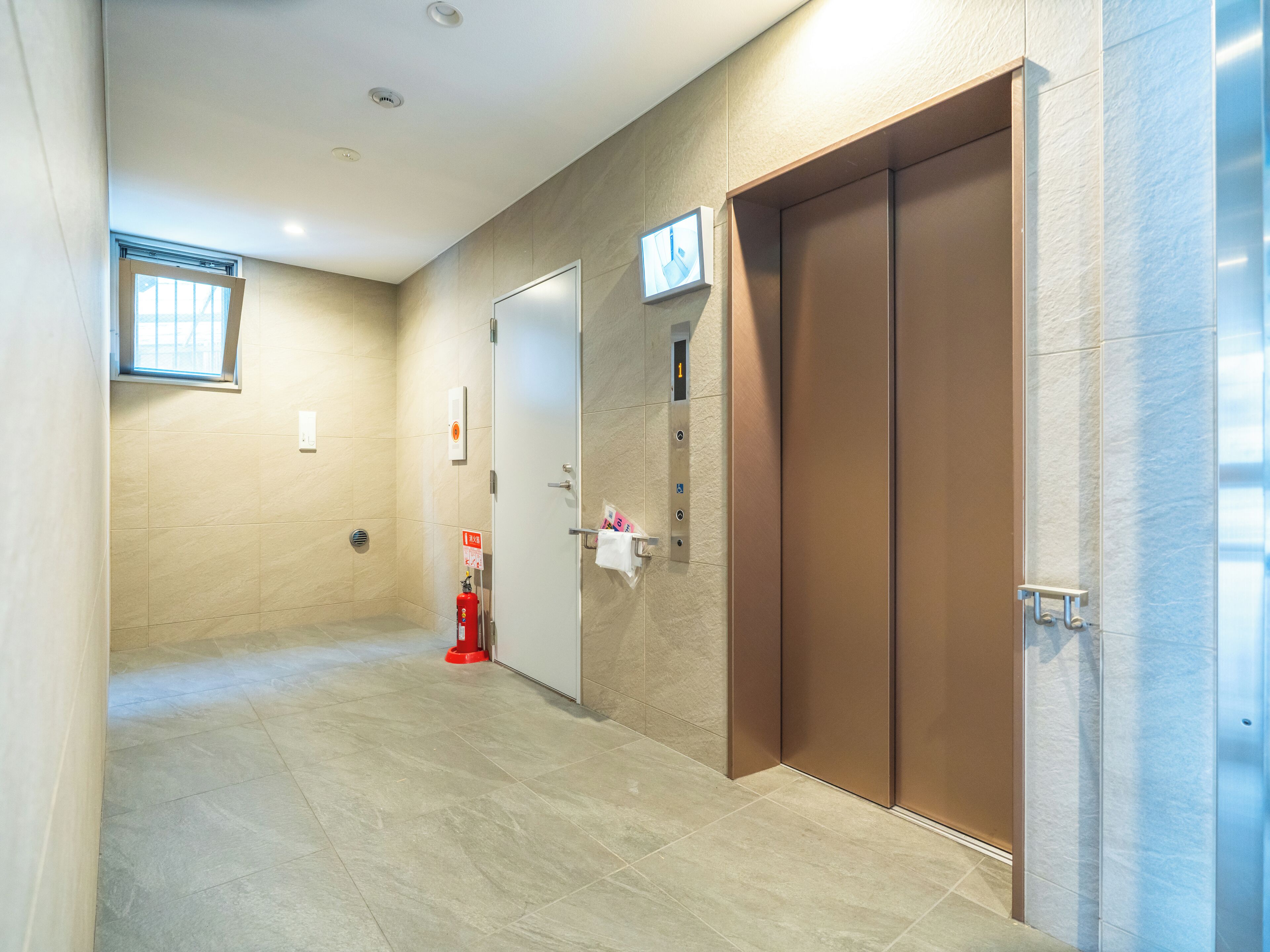 A hallway with a fire extinguisher, a door with a sign, and an elevator.