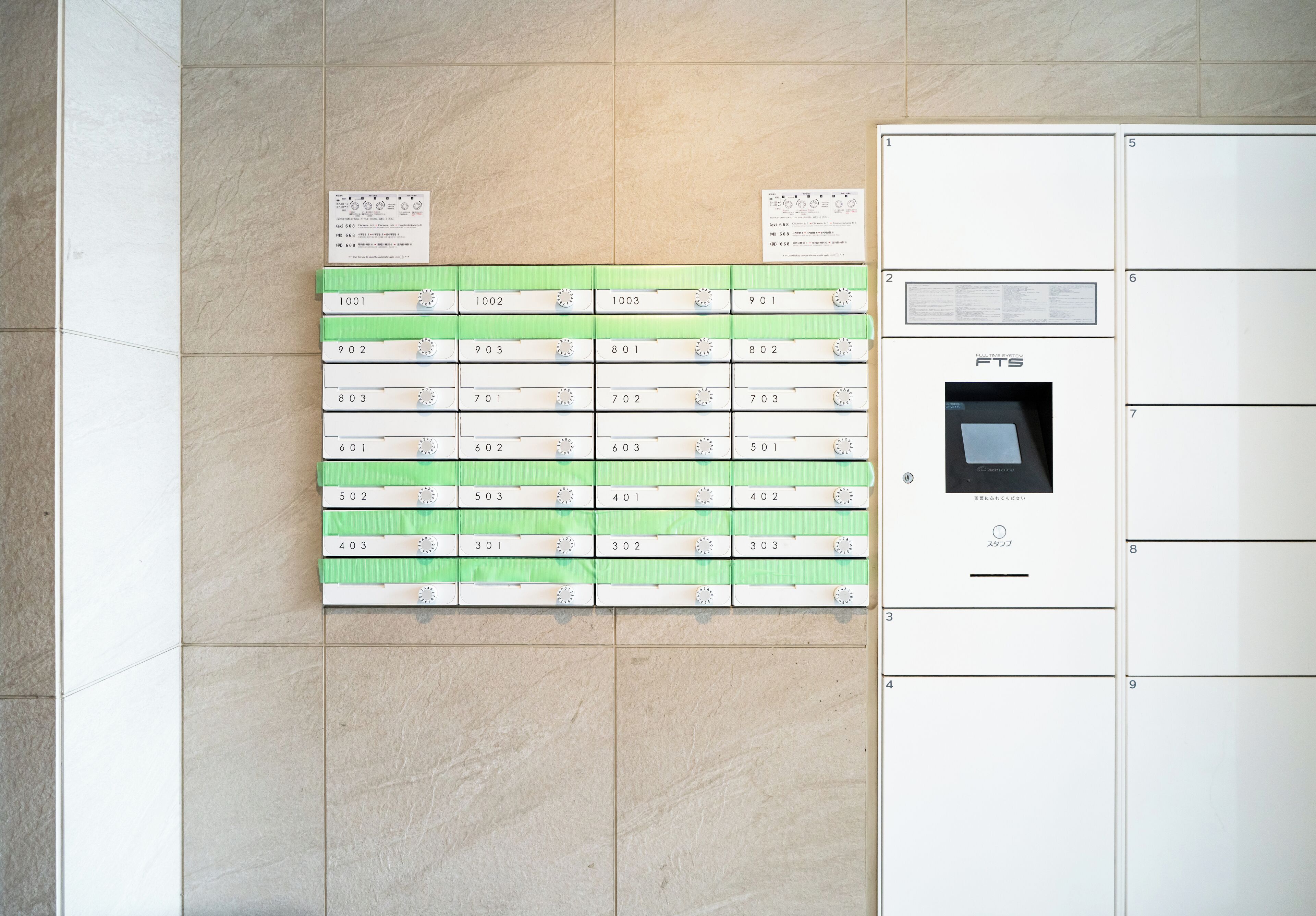 A wall with numbered storage boxes and a security keypad.
