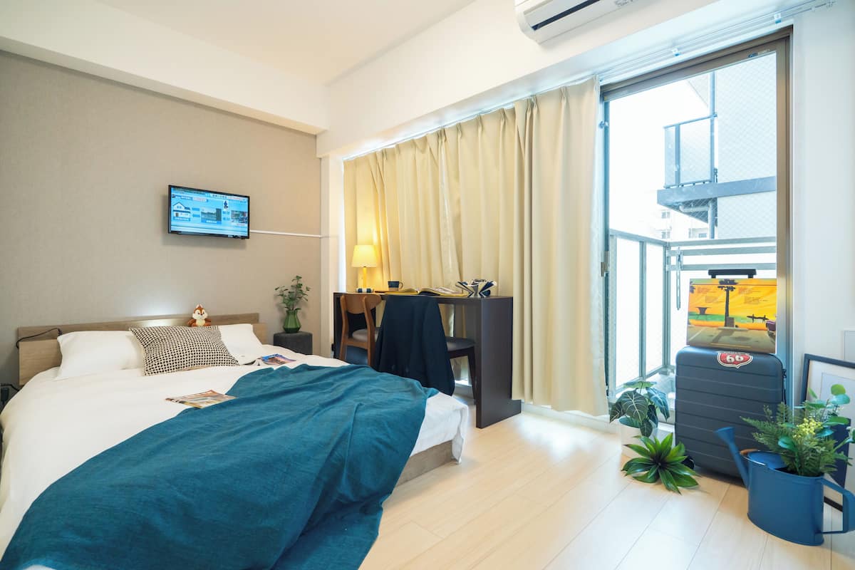 Une chambre d’hôtel avec un lit, un bureau, une chaise, une télévision et une fenêtre avec des rideaux.