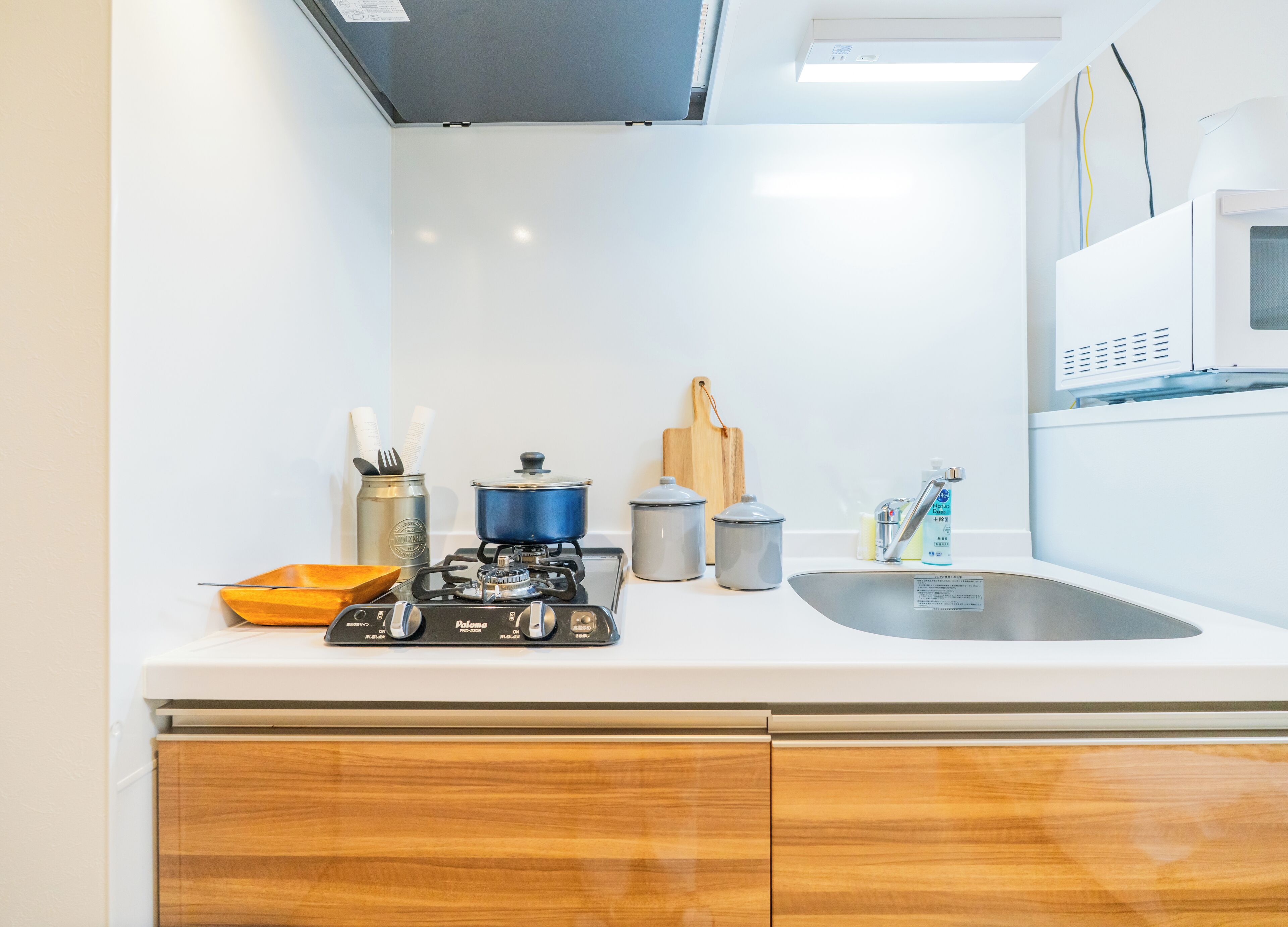 A modern kitchen with white cabinets, a gas stove, a microwave, and a sink.