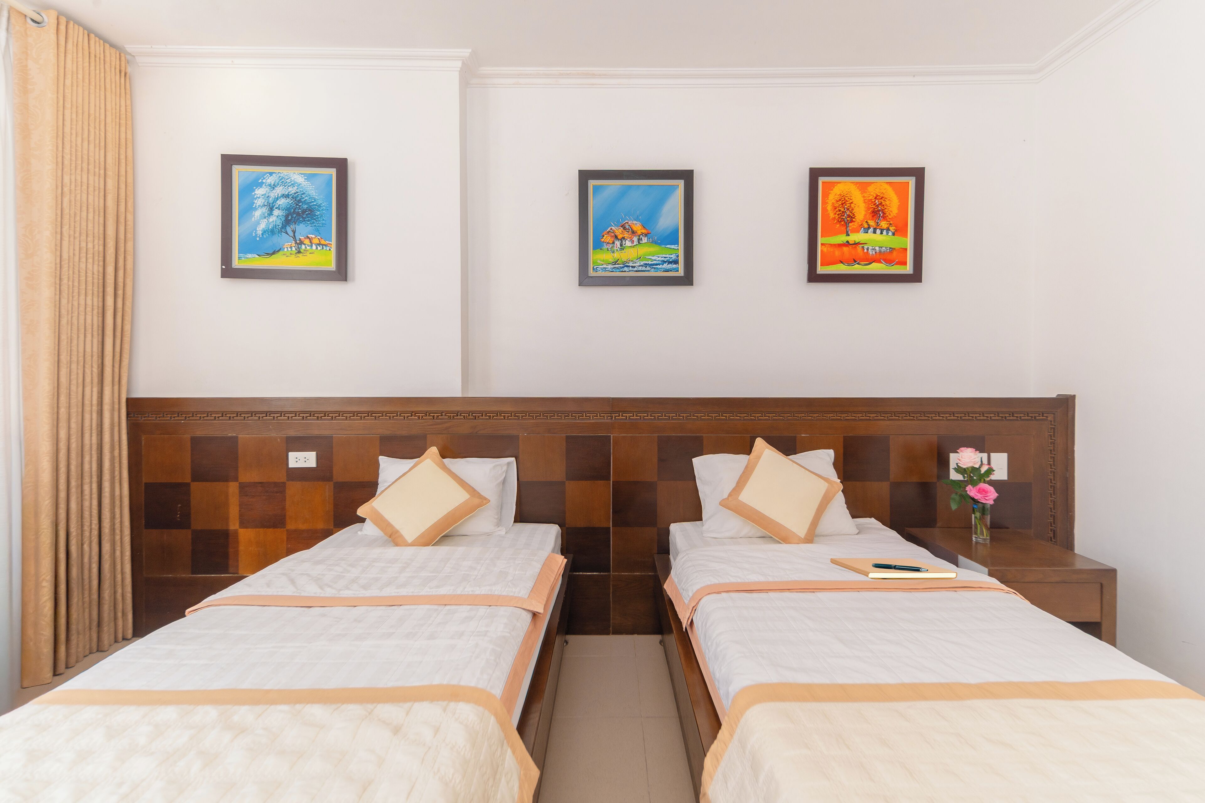 Una habitación de hotel con dos camas, un cabecero de madera y tres cuadros enmarcados en la pared.