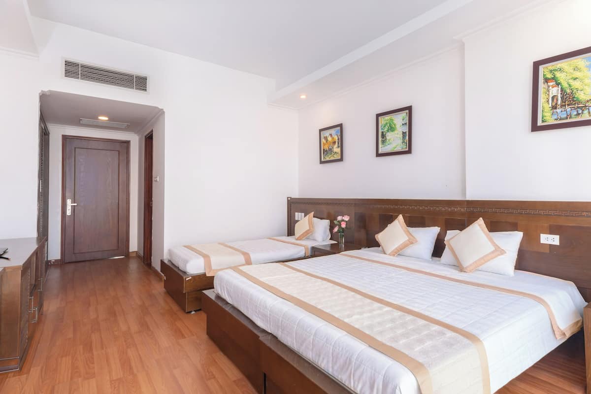 Una camera d'albergo con due letti, una scrivania e una porta.